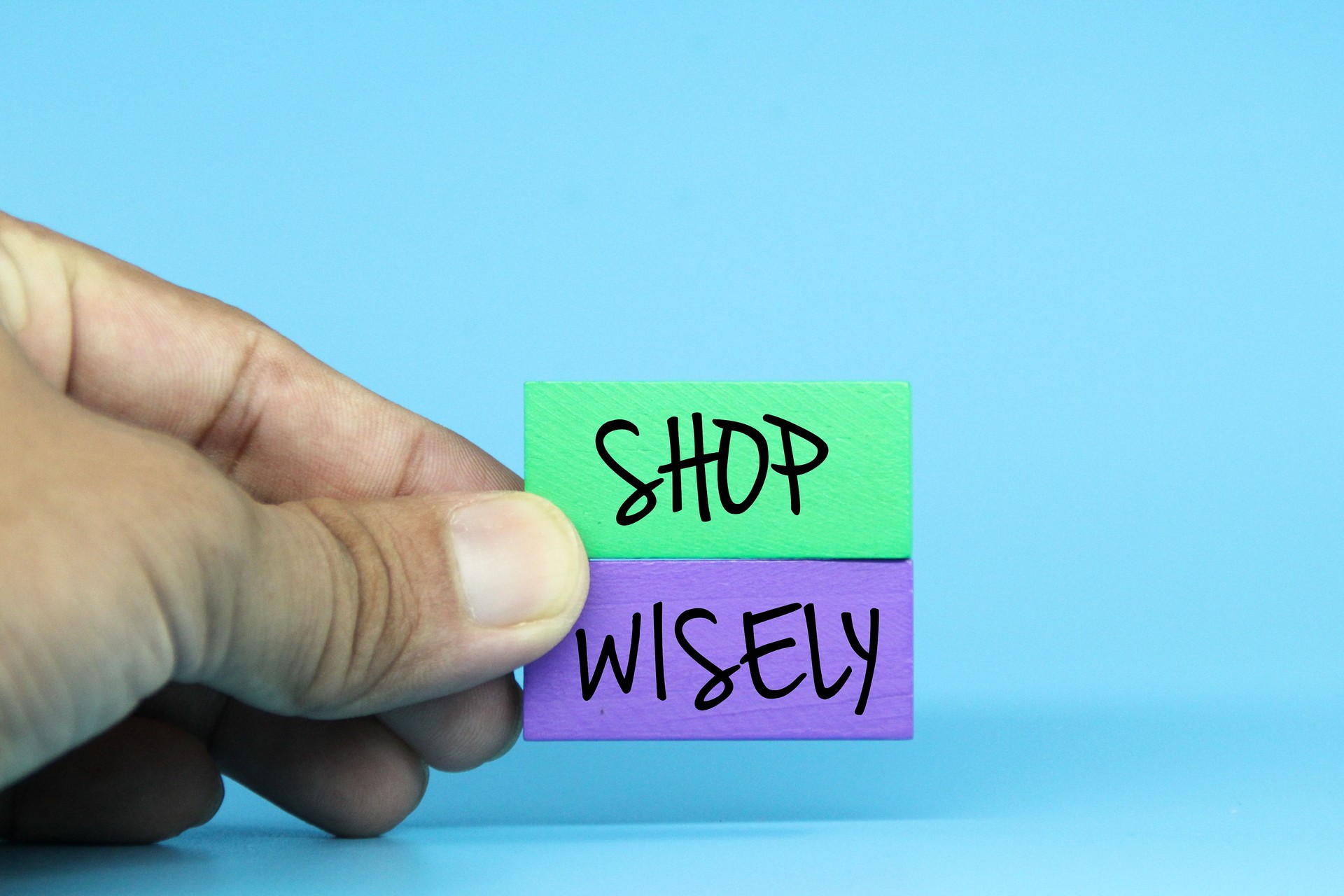 hands holding colored blocks with the word shop wisely. Selective focus